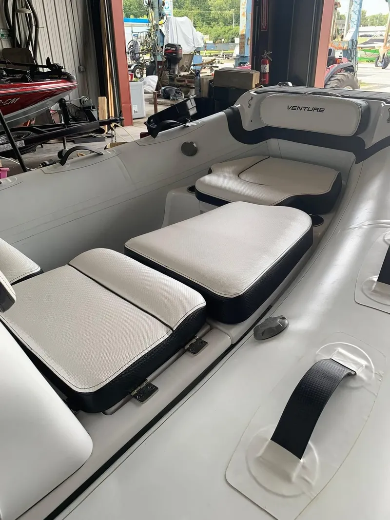 Slide: The Image of 2021 Walker Bay Venture 14 boat interior with cushioned seating in a garage setting. - 4