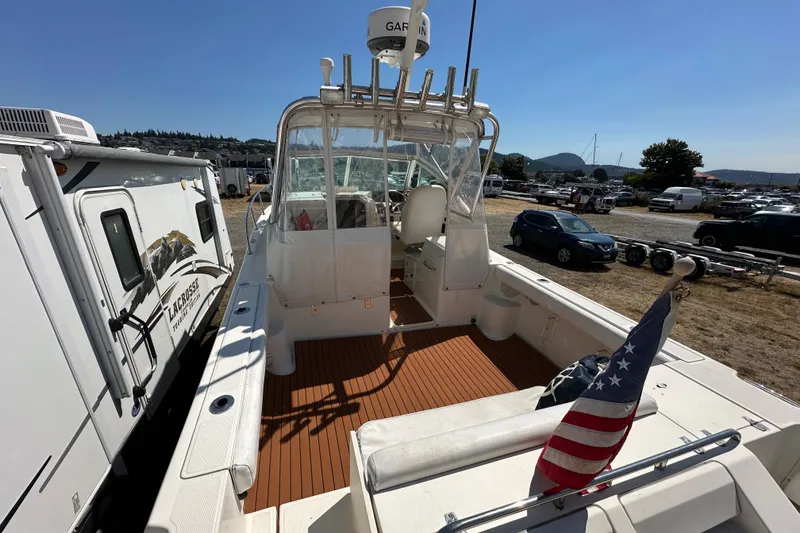 Slide: The Image of 2002 Pursuit 2860 Denali boat with American flag, parked near RVs and cars. - 11