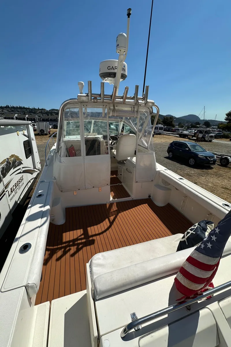Slide: The Image of 2002 Pursuit 2860 Denali boat with wooden deck and American flag, docked outdoors. - 12