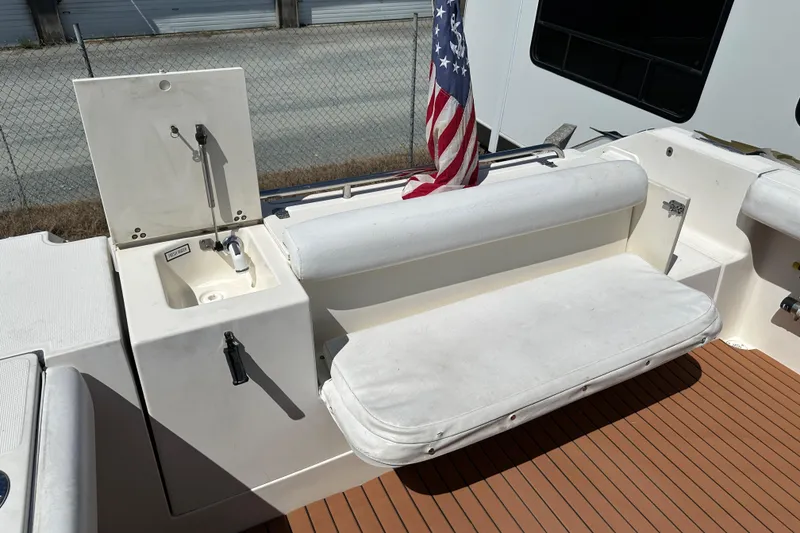 Slide: The Image of 2002 Pursuit 2860 Denali boat interior with sink, cushioned seating, and American flag. - 15