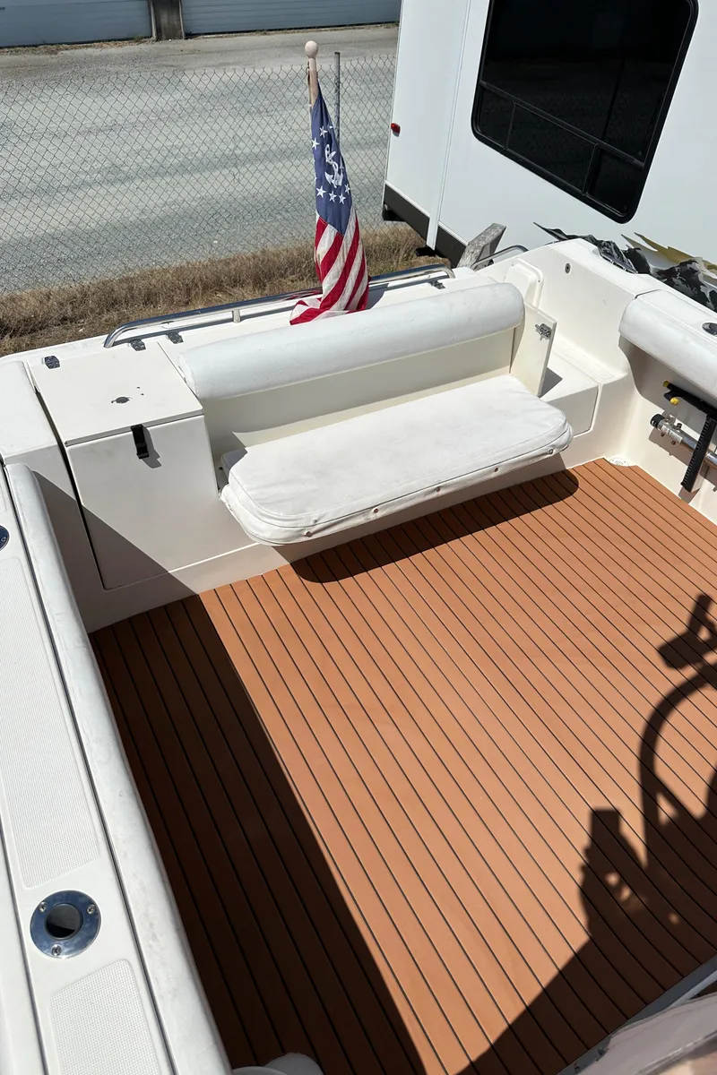 Slide: The Image of 2002 Pursuit 2860 Denali boat deck with American flag and cushioned seating. - 17