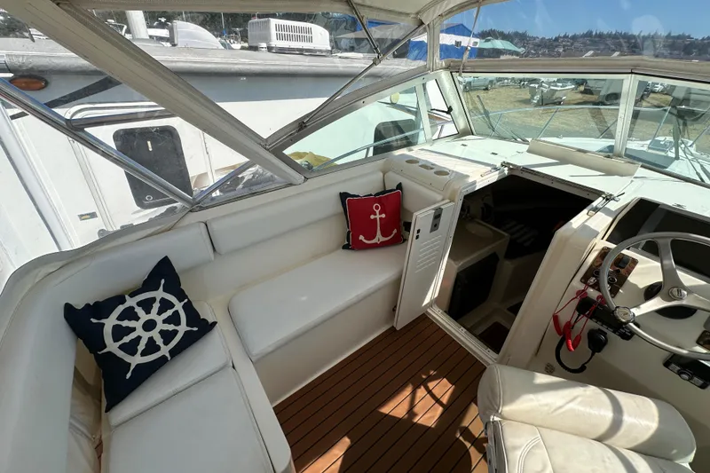 Slide: The Image of 2002 Pursuit 2860 Denali boat interior with nautical-themed cushions and steering wheel. - 25