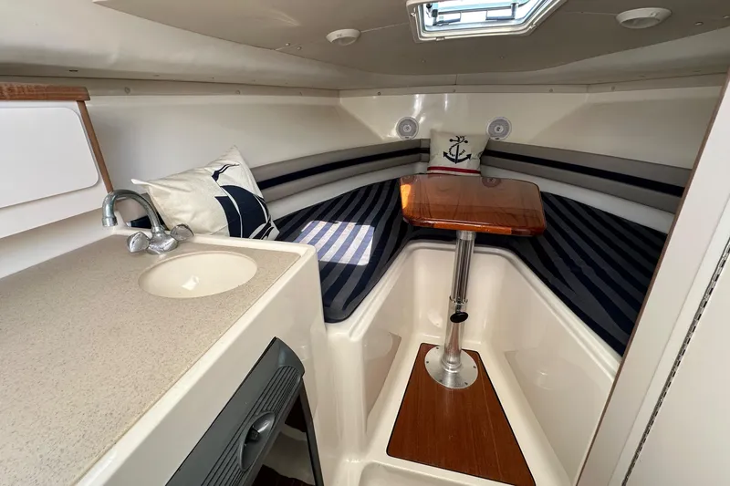 Slide: The Image of 2002 Pursuit 2860 Denali cabin interior with striped seating, wooden table, and compact sink. - 28