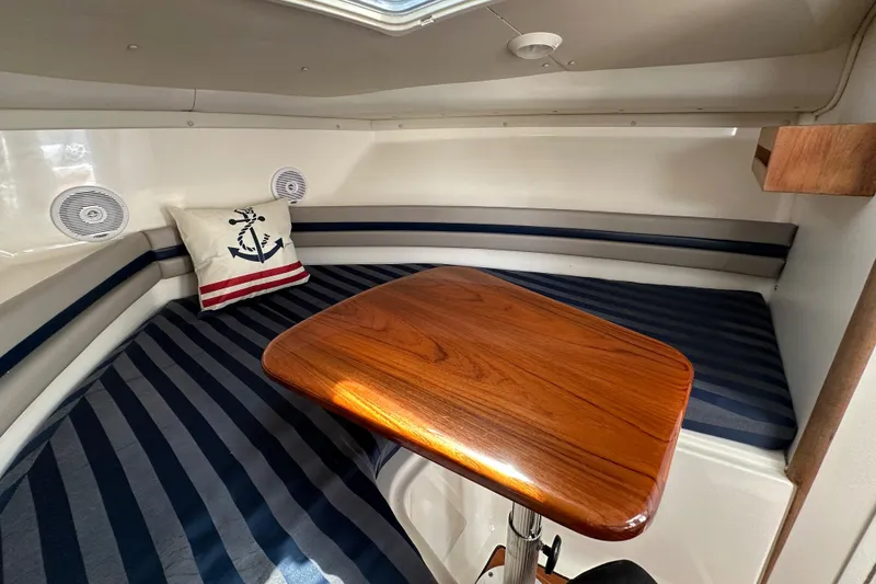 Slide: The Image of Interior of 2002 Pursuit 2860 Denali boat with striped seating and wooden table. - 29