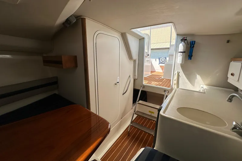 Slide: The Image of Interior of 2002 Pursuit 2860 Denali boat with wooden table, sink, and ladder. - 33
