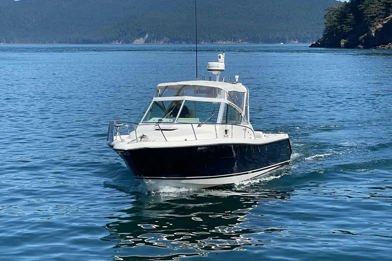 Slide: The Image of 2002 Pursuit 2860 Denali boat cruising on a serene lake with forested hills. - 53