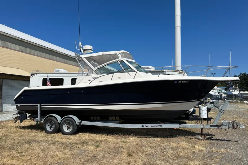 Slide: The Image of 2002 Pursuit 2860 Denali boat on trailer, parked outdoors near a building. - 6