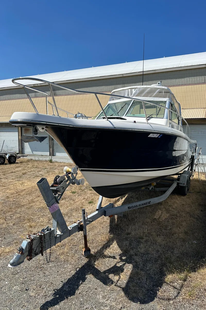 Slide: The Image of 2002 Pursuit 2860 Denali boat on trailer, parked outdoors under clear blue sky. - 8