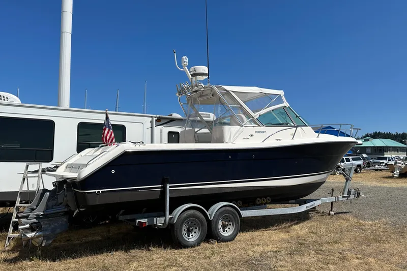 Slide: The Image of 2002 Pursuit 2860 Denali boat on trailer, parked outdoors under clear blue sky. - 9