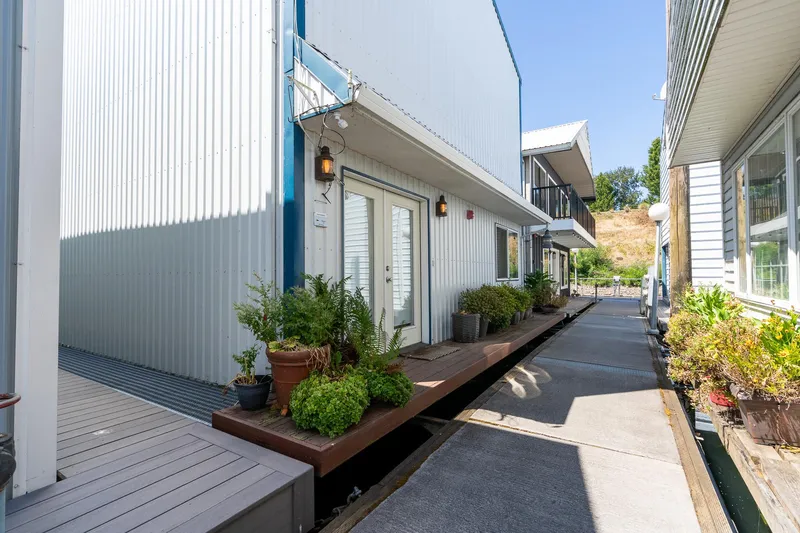 The Image of Modern Steelhead Boathouse, 2006, with potted plants and walkway, under clear blue sky. - 0