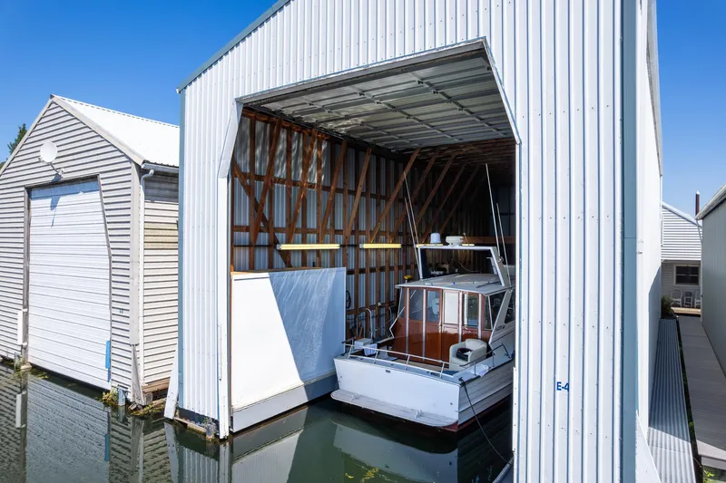 Slide: The Image of Custom Steelhead Boathouse 2006 with boat inside, open door, sunny day, waterfront location. - 11
