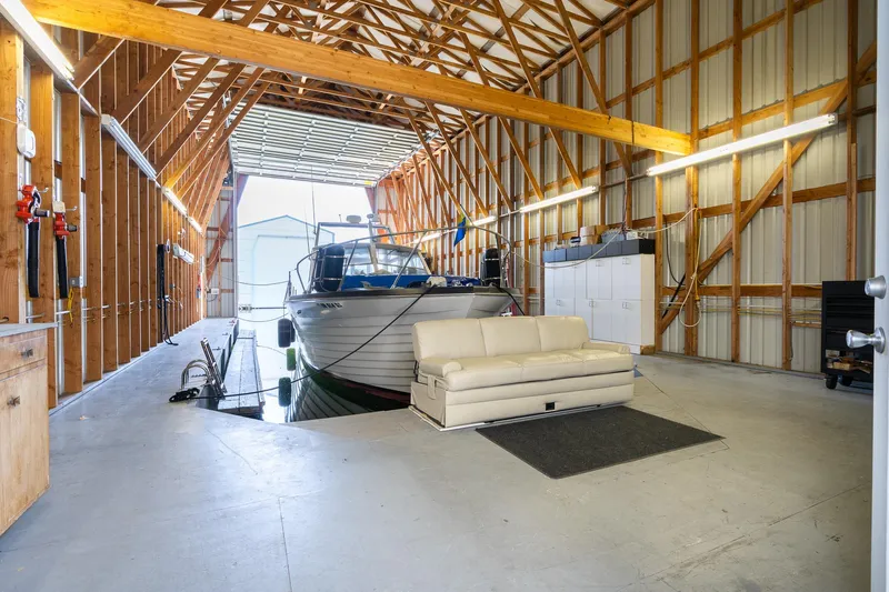 Slide: The Image of Spacious boathouse interior with docked boat and cozy seating area, 2006 Steelhead model. - 3