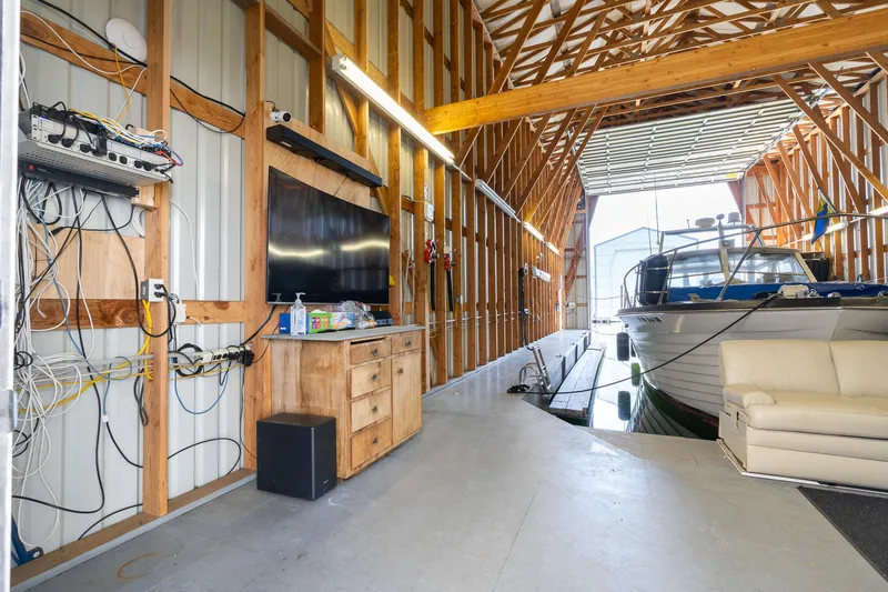 Slide: The Image of Modern boathouse interior with boat, TV, and sofa, featuring exposed wooden beams. - 4