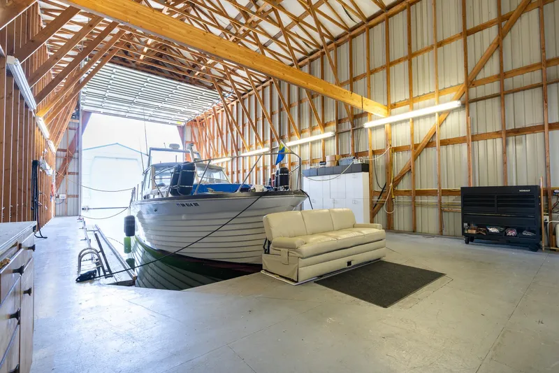 Slide: The Image of Interior of a 2006 Custom Steelhead Boathouse with docked boat and sofa. - 5