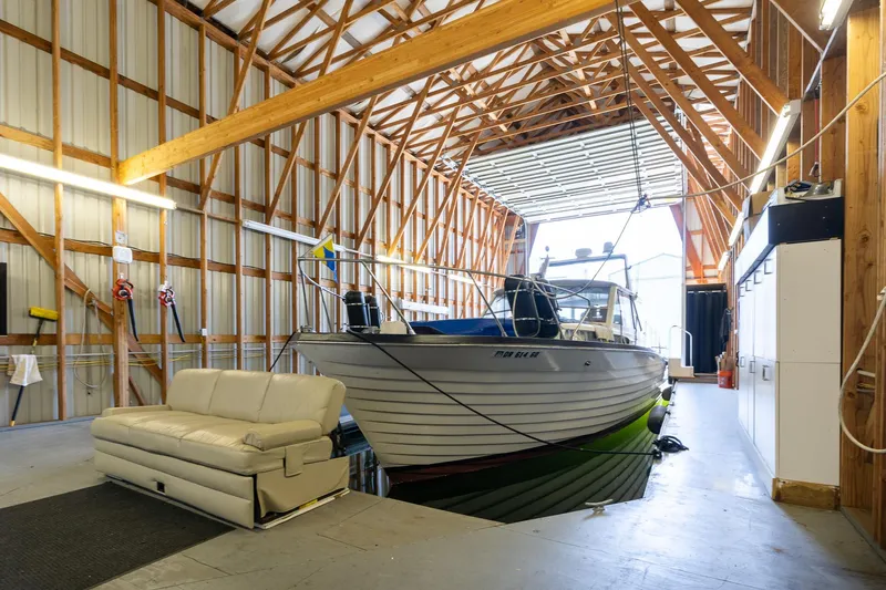 Slide: The Image of Custom Steelhead Boathouse 2006 with boat and sofa inside, featuring wooden beams and storage cabinets. - 6