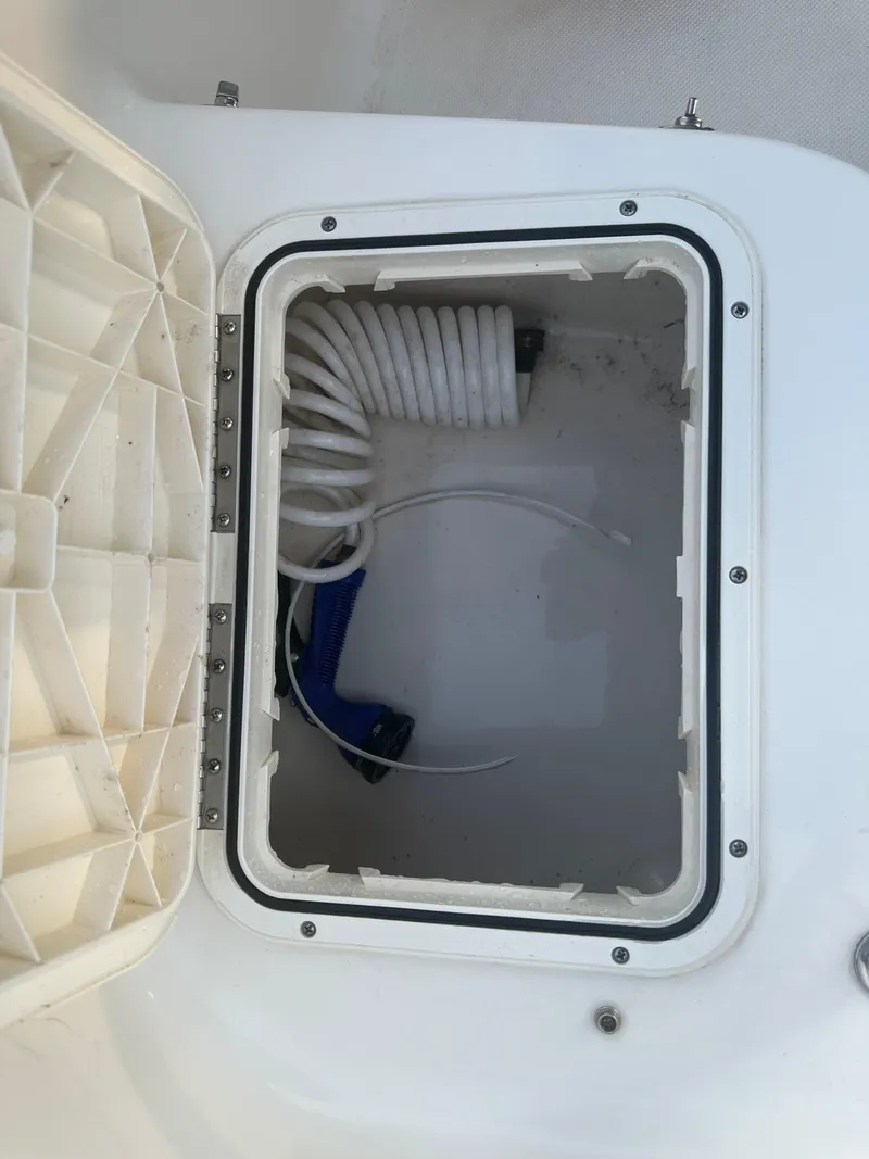 Slide: The Image of Open storage compartment on 2024 Pioneer 202 Sportfish boat with coiled hose inside. - 24