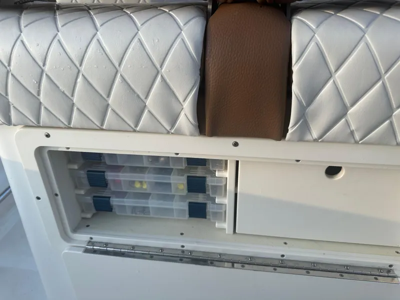 Slide: The Image of 2024 Pioneer 202 Sportfish storage compartment with tackle boxes and quilted seating. - 31