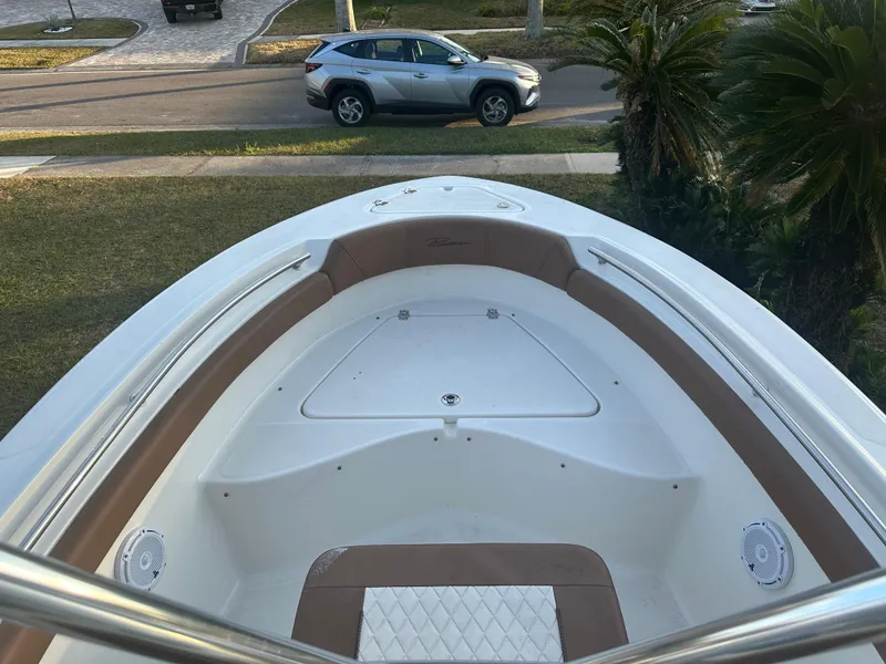Slide: The Image of 2024 Pioneer 202 Sportfish boat interior with tan seating, parked car in background. - 44
