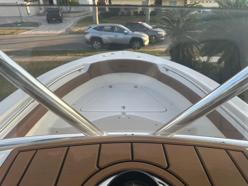 Slide: The Image of 2024 Pioneer 202 Sportfish boat deck with stainless steel railings, parked cars in background. - 45