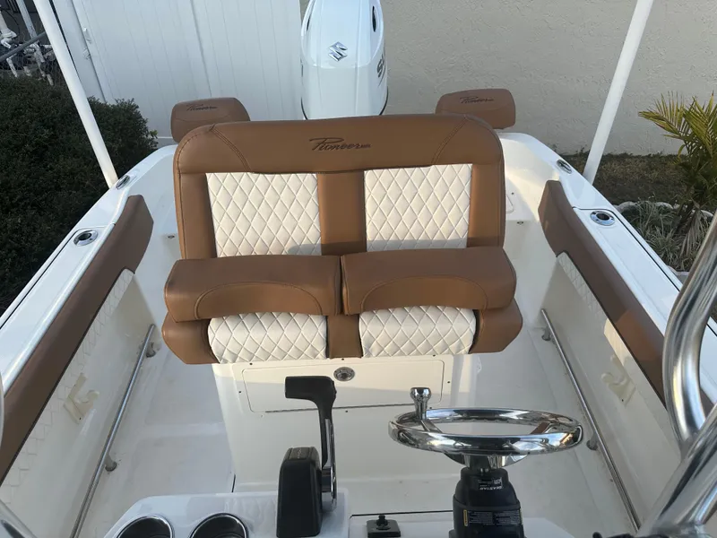 Slide: The Image of 2024 Pioneer 202 Sportfish boat interior with tan and white seating, steering wheel, and controls. - 46