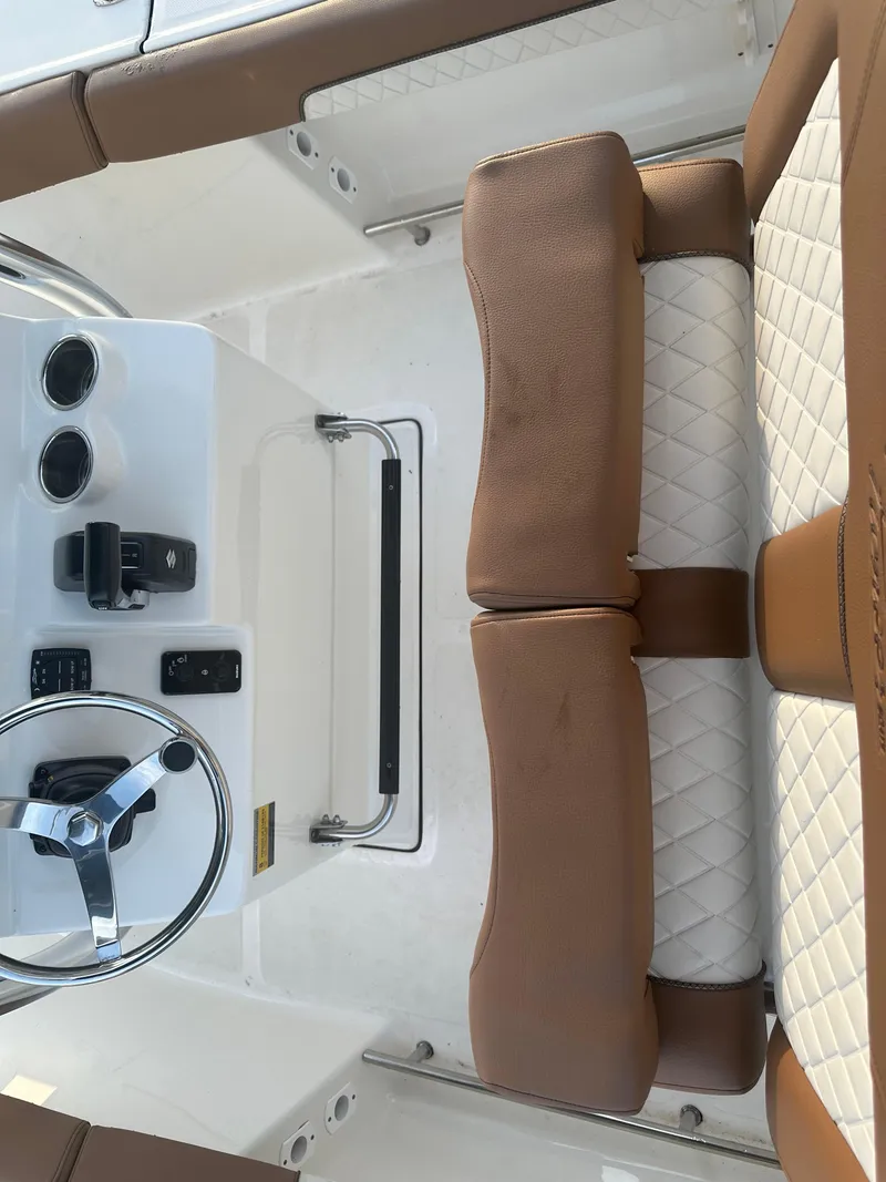 Slide: The Image of 2024 Pioneer 202 Sportfish boat interior with brown and white seating, steering wheel, and controls. - 47