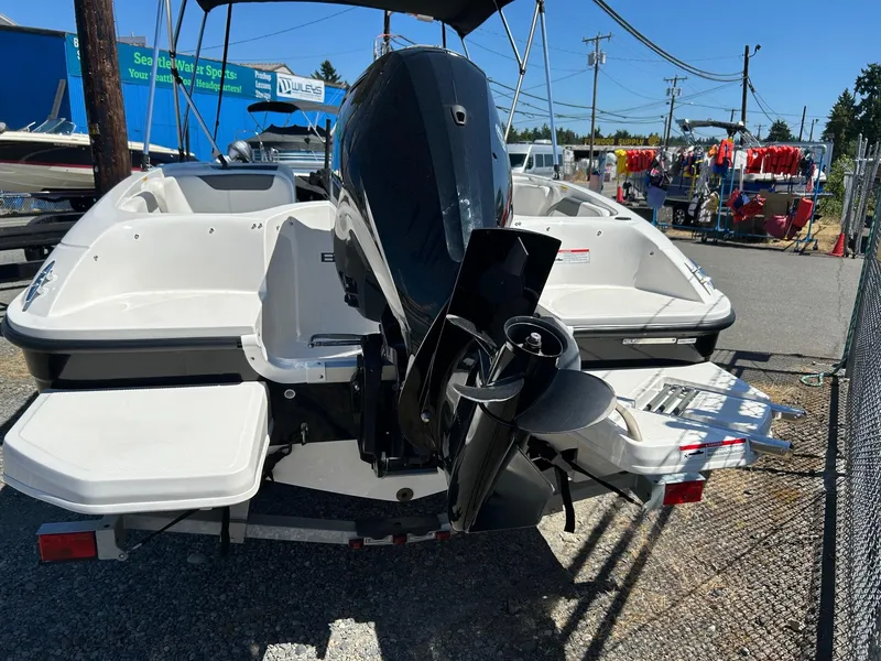 Slide: The Image of 2020 Bayliner Element E18 boat with outboard motor, displayed outdoors at a dealership. - 14