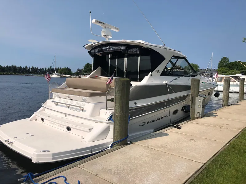 Slide: The Image of 2015 Regal 46 Sport Coupe yacht docked by a serene waterfront. - 2