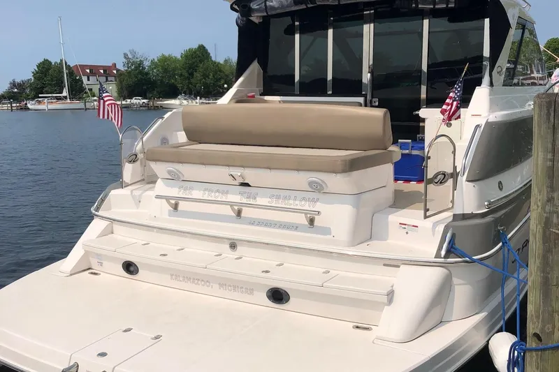 Slide: The Image of 2015 Regal 46 Sport Coupe yacht docked, featuring a spacious rear deck and American flags. - 3