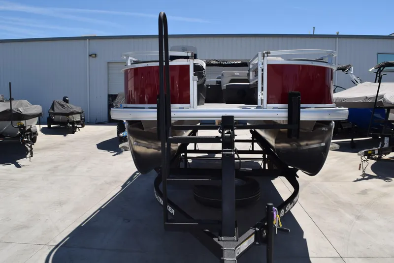 Slide: The Image of 2026 Sun Tracker Bass Buggy 18 DLX pontoon boat on trailer, parked outdoors. - 3