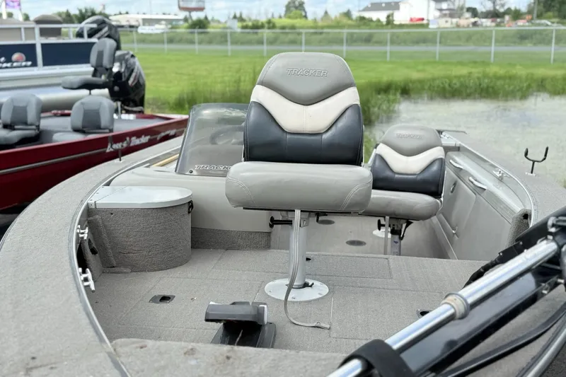 Slide: The Image of 2000 Tracker Targa 17 boat interior with seating and steering, docked near grassy area. - 4