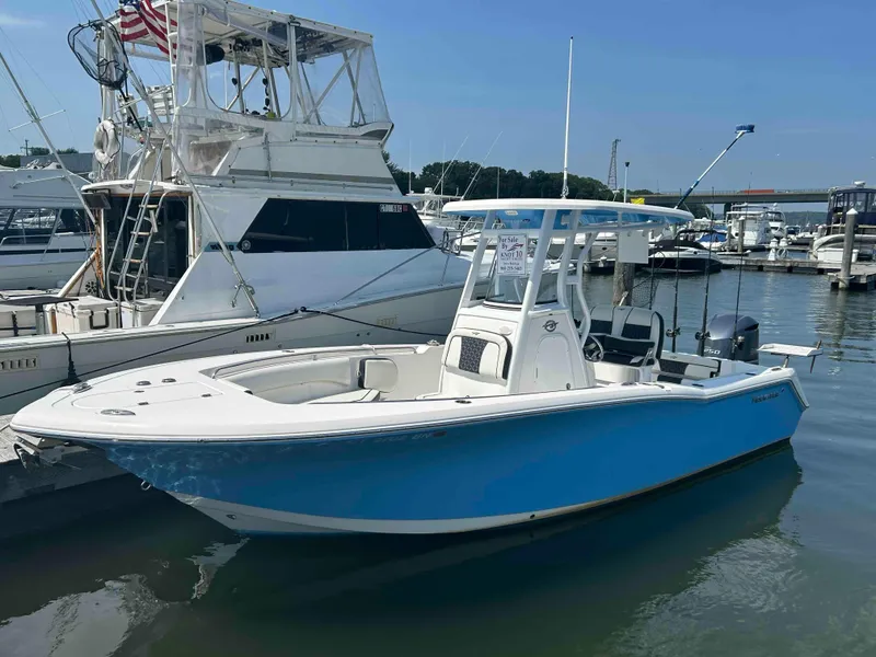 The Image of 2021 Tidewater 232 CC Adventure boat docked at marina, blue hull, clear sky. - 0