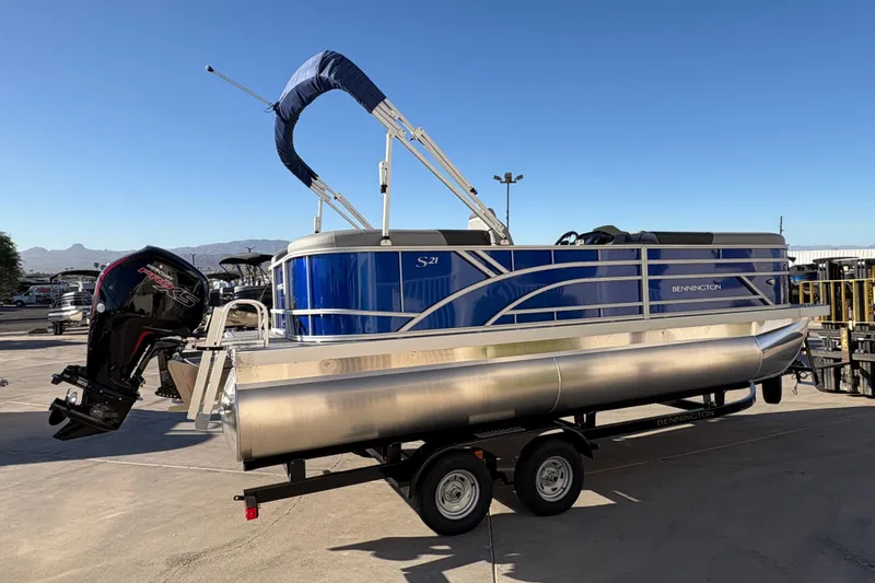 Slide: The Image of 2026 Bennington 21 SSR pontoon boat on trailer, blue exterior, outboard motor, sunny day. - 3