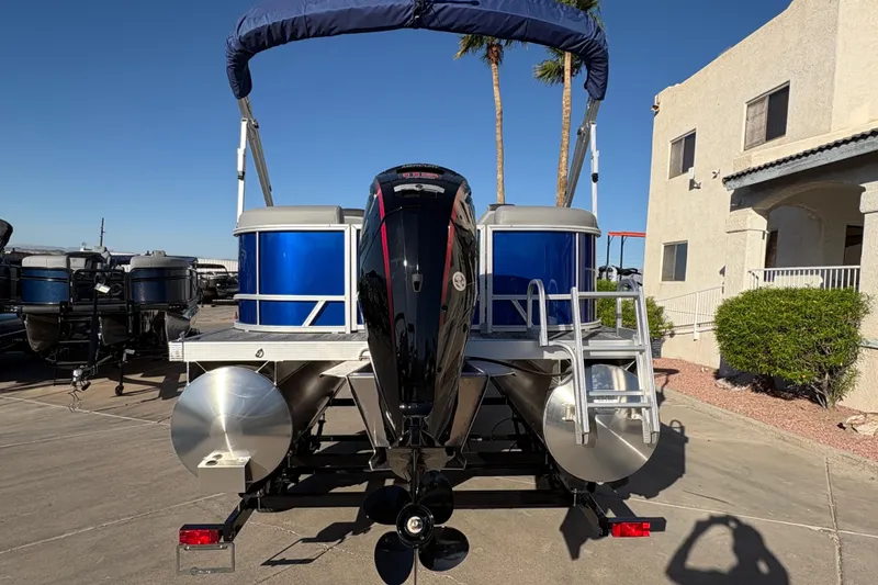 Slide: The Image of 2026 Bennington 21 SSR pontoon boat with blue panels and outboard motor, parked outdoors. - 4