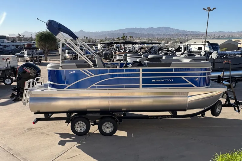 Slide: The Image of 2026 Bennington 21 SSR pontoon boat on trailer, blue and silver design, outdoor dealership setting. - 5