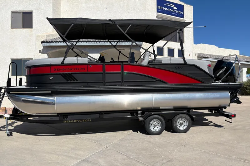 The Image of 2026 Bennington 22 MFB pontoon boat on trailer, black and red design, parked outdoors. - 0
