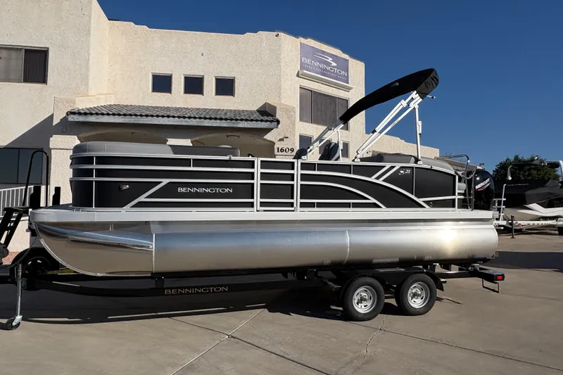 The Image of 2026 Bennington 21 SSB pontoon boat on trailer, parked outside dealership. - 0