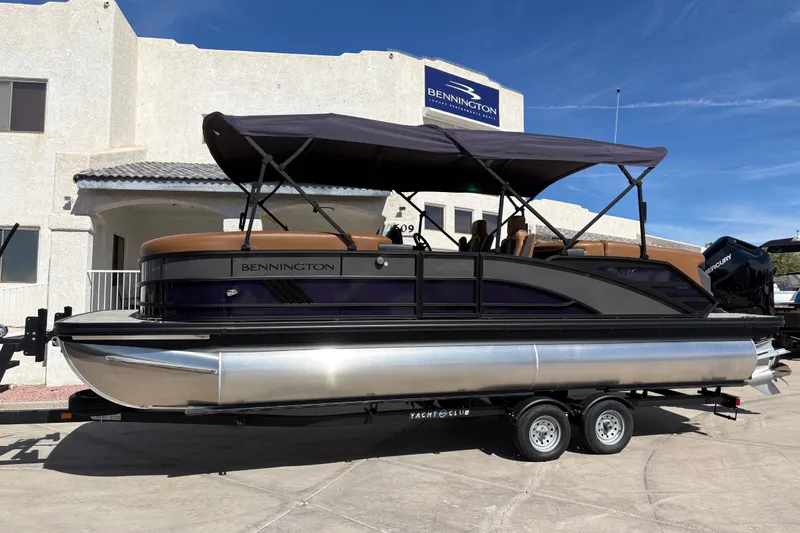 The Image of 2026 Bennington 24 MFB pontoon boat on trailer, parked outside dealership. - 0