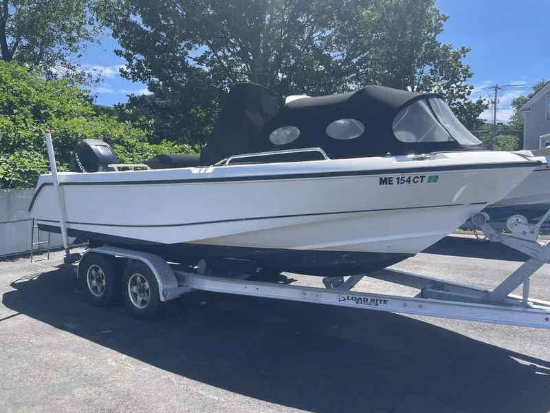 Slide: The Image of 2006 Boston Whaler 210 Outrage boat on trailer, covered, parked outdoors. - 3