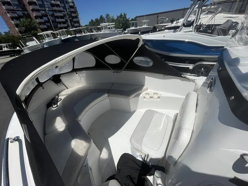 Slide: The Image of 2006 Boston Whaler 210 Outrage boat interior with seating and canopy, docked near other boats. - 5