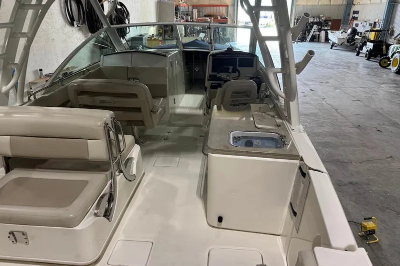 Slide: The Image of 2022 Boston Whaler 320 Vantage interior with seating and helm in a warehouse setting. - 11