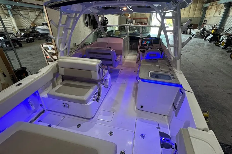 Slide: The Image of 2022 Boston Whaler 320 Vantage interior with seating and blue LED lighting in a warehouse. - 19