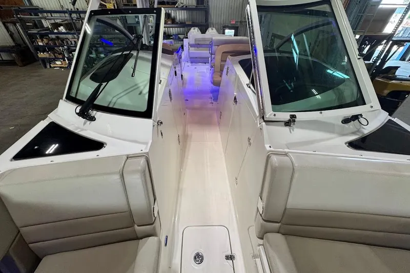 Slide: The Image of 2022 Boston Whaler 320 Vantage interior with seating and windshield in a warehouse setting. - 27