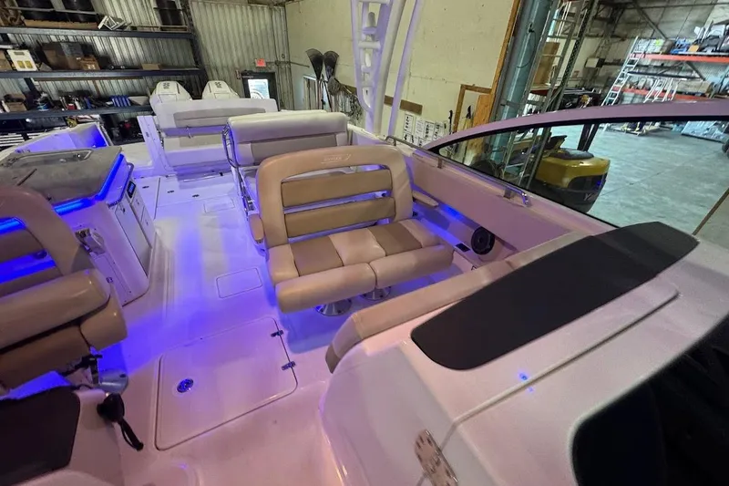 Slide: The Image of 2022 Boston Whaler 320 Vantage interior with beige seating and blue ambient lighting. - 29