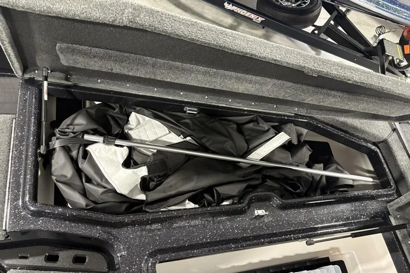 Slide: The Image of Open storage compartment in a 2026 Skeeter ZXE20 boat, containing folded fabric and a metal rod. - 12