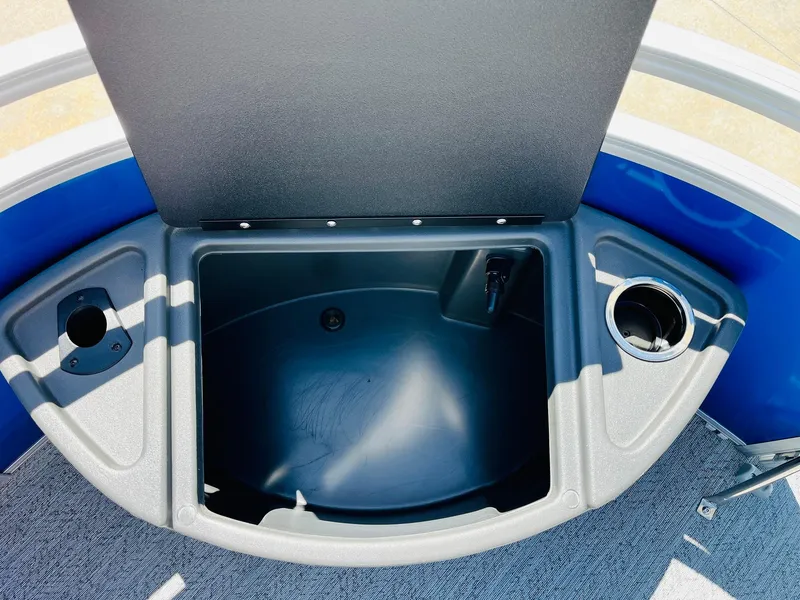Slide: The Image of 2026 Sun Tracker Fishin' Barge 20 DLX storage compartment with cup holders and blue accents. - 15