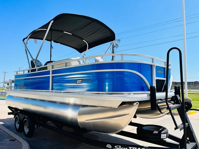 Slide: The Image of 2026 Sun Tracker Fishin' Barge 20 DLX pontoon boat on trailer, blue exterior, sunny day. - 4