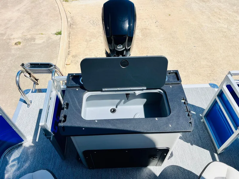 Slide: The Image of 2026 Sun Tracker Fishin' Barge 20 DLX with open storage compartment and motor, viewed from above. - 46