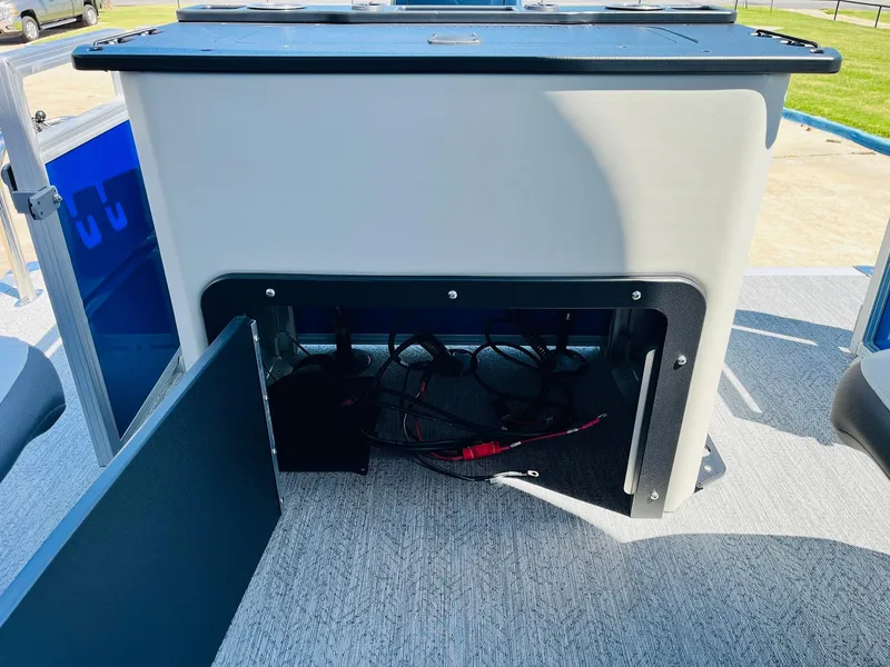 Slide: The Image of 2026 Sun Tracker Fishin' Barge 20 DLX storage compartment with open door and visible wiring. - 48