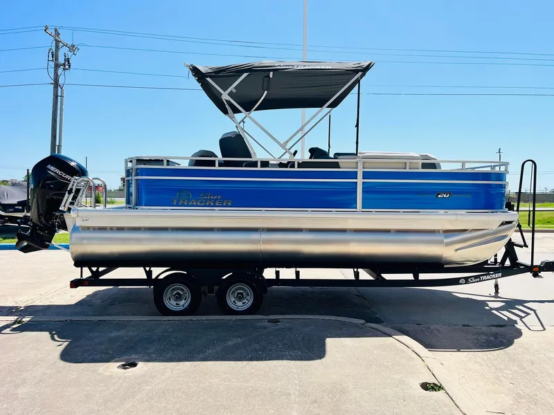 Slide: The Image of 2026 Sun Tracker Fishin' Barge 20 DLX pontoon boat on trailer, side view. - 5