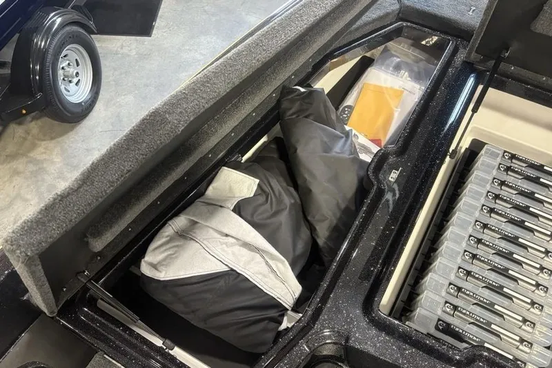 Slide: The Image of Open storage compartment in 2026 Skeeter ZXE20 boat, showing gear and tackle boxes. - 10